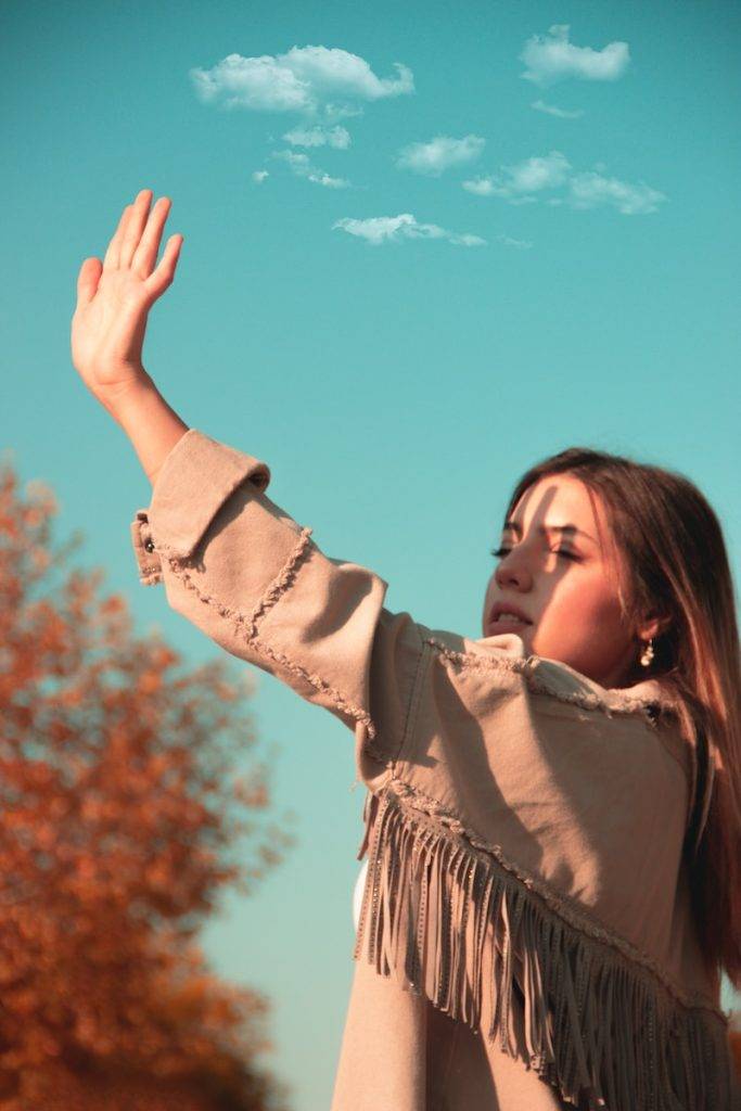 woman in brown long sleeve shirt raising her right hand