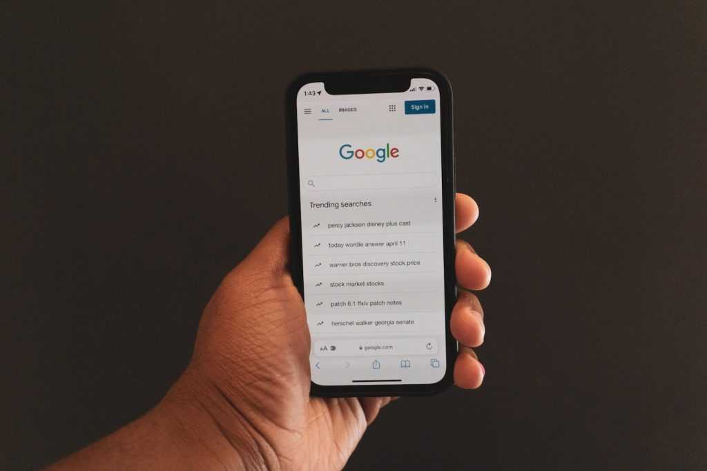 a person holding up a cell phone with the google logo on it
